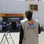 A SUSALUD official outside an emergency entrance at a hospital during the day.