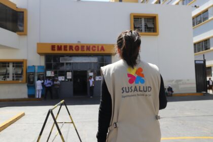 A SUSALUD official outside an emergency entrance at a hospital during the day.