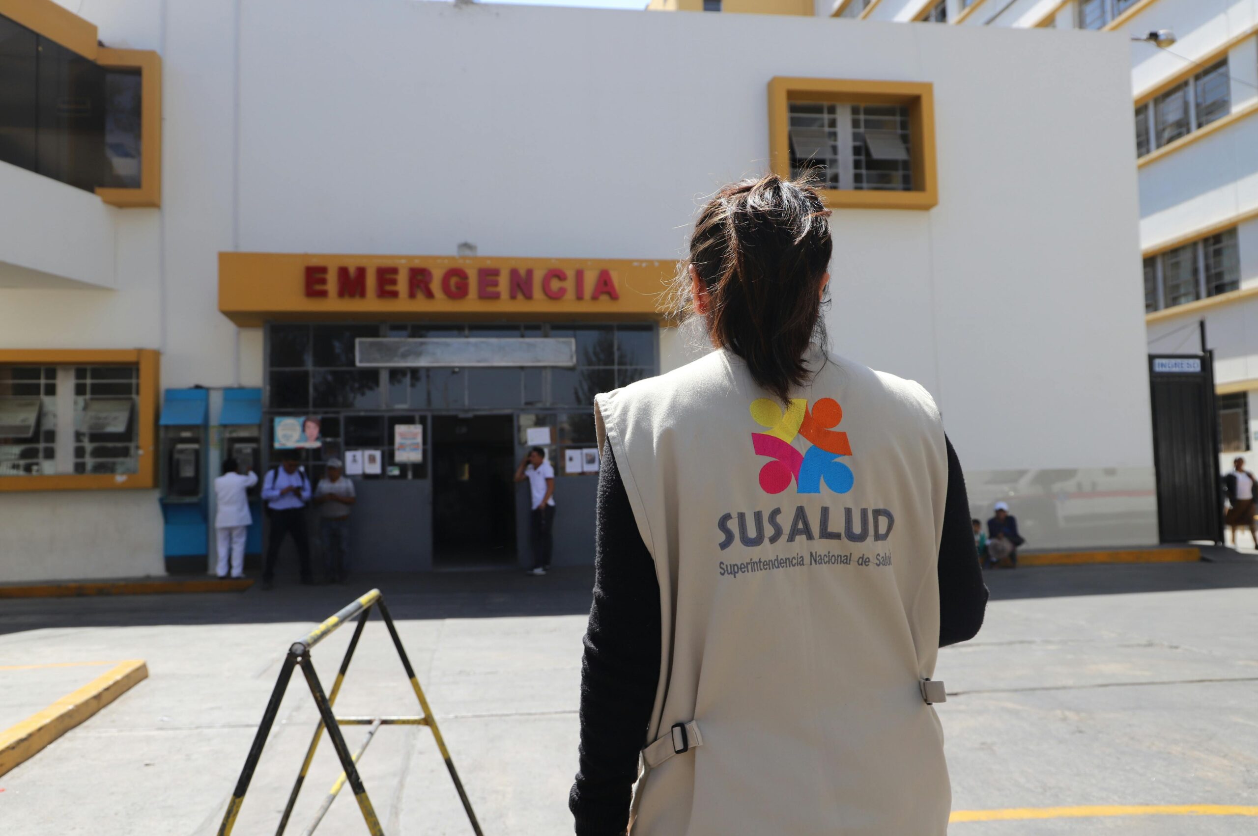 A SUSALUD official outside an emergency entrance at a hospital during the day.