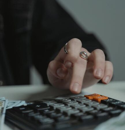 A person's hand with rings presses keys on a calculator in a focused setting.