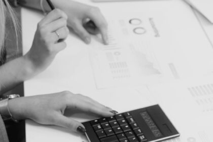 Two colleagues reviewing financial reports with a calculator in a modern workspace.