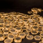 Close-up of a pile of Euro coins scattered on a black surface, representing wealth and finance.